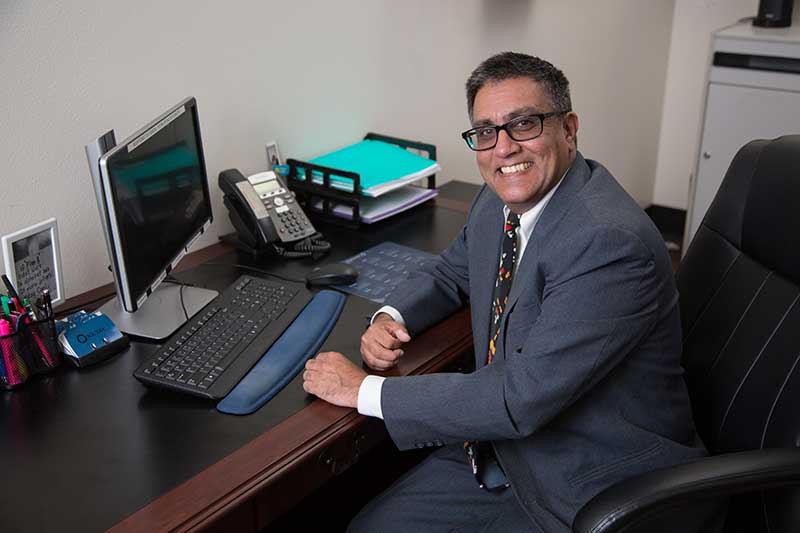 Locums physician, Dr. Moojani, sits as his desk and smiles