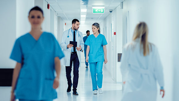 Advanced Practitioner walks through busy hospital
