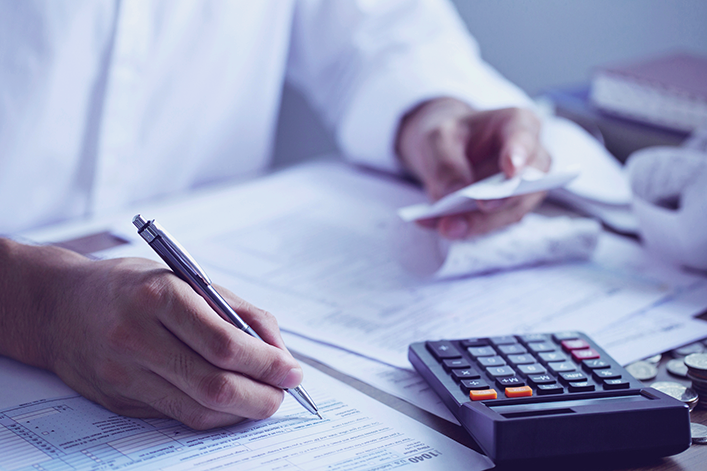 Clinician sits at desk with tax forms and calculator