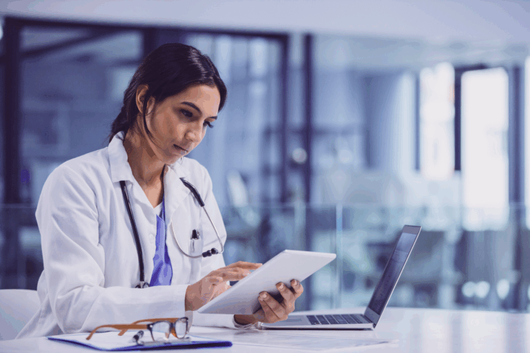 Female physician using tablet and laptop