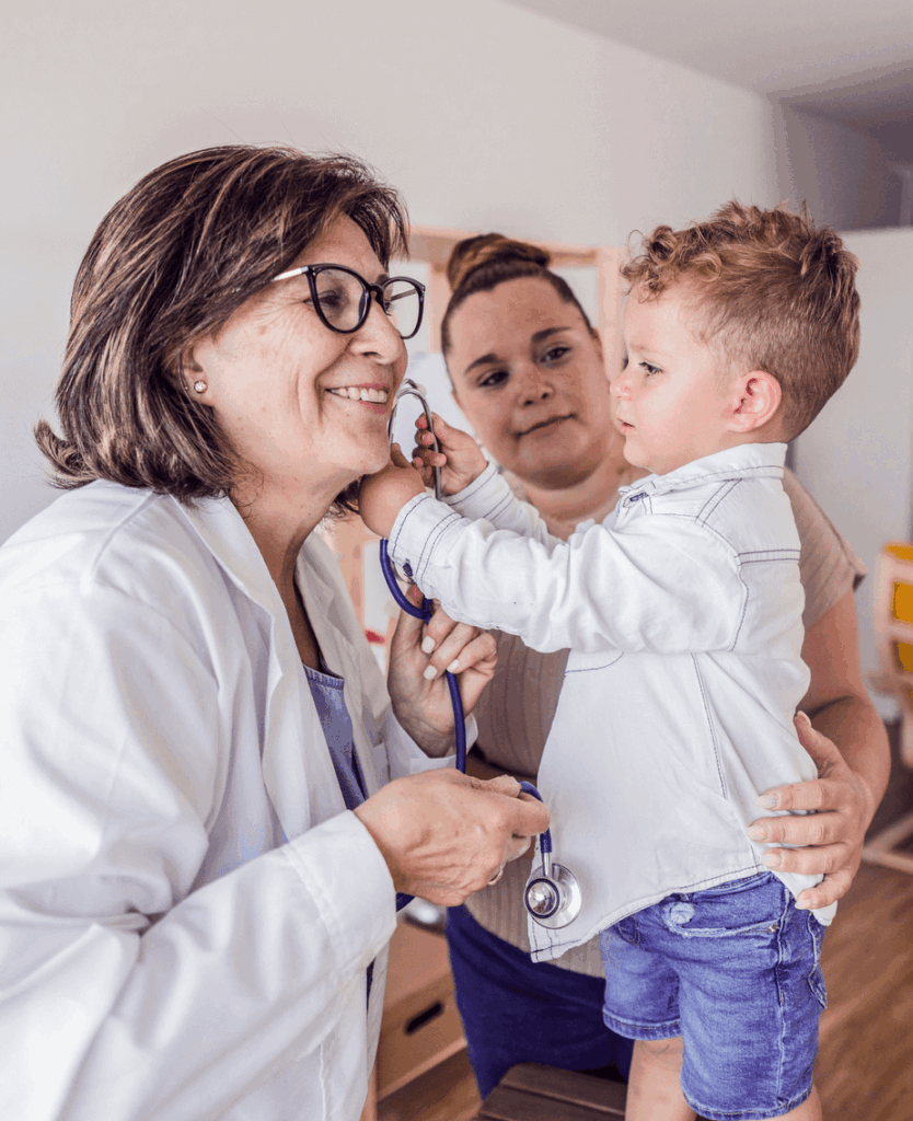 Female doctor smiling at little boy playing with stethoscope