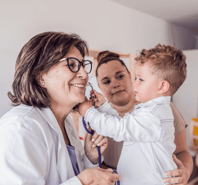 Female doctor smiling at little boy playing with stethoscope