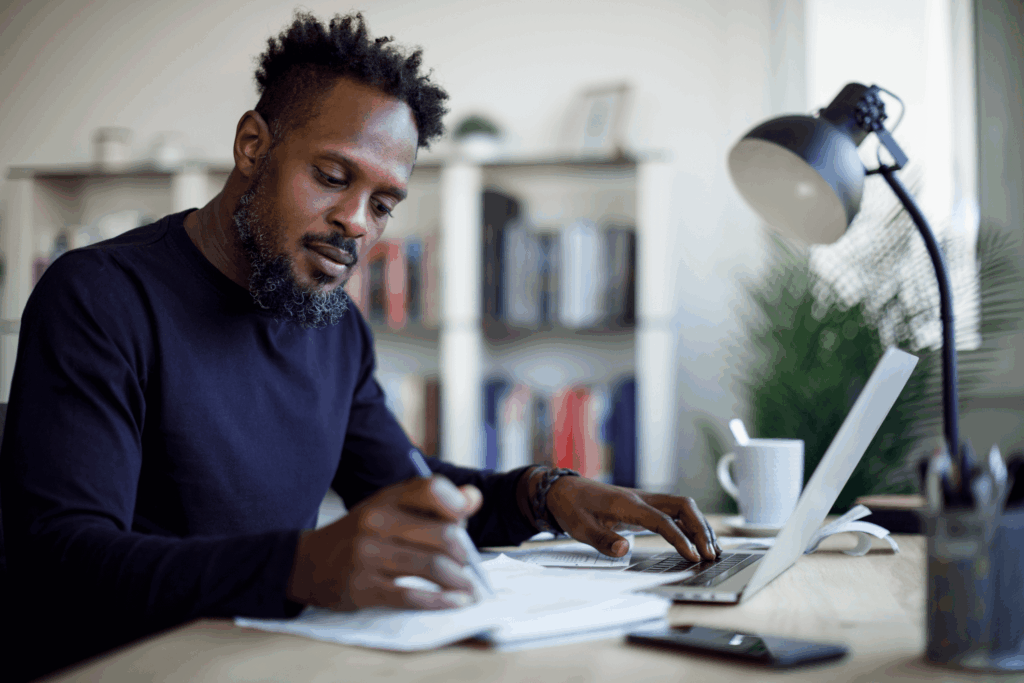 Man sitting at a laptop with a pen and paper