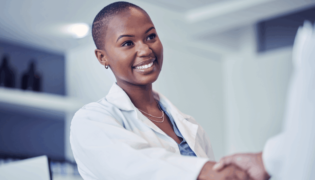 Female doctor smiling and shaking someone's hand
